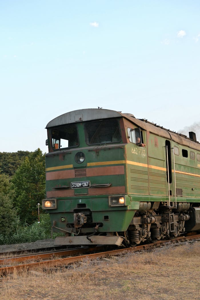 A green diesel locomotive traveling on a railway track during the day.